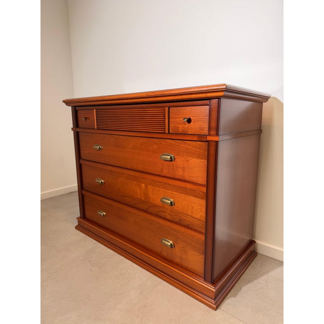 Elegant cherrywood chest of drawers featuring a timeless design with warm wood tones and refined brass-effect hardware....
