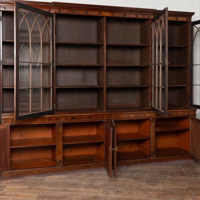 Early 20th century English bookcase crafted in mahogany. The crown is decorated with a carved Greek key meander pattern,...