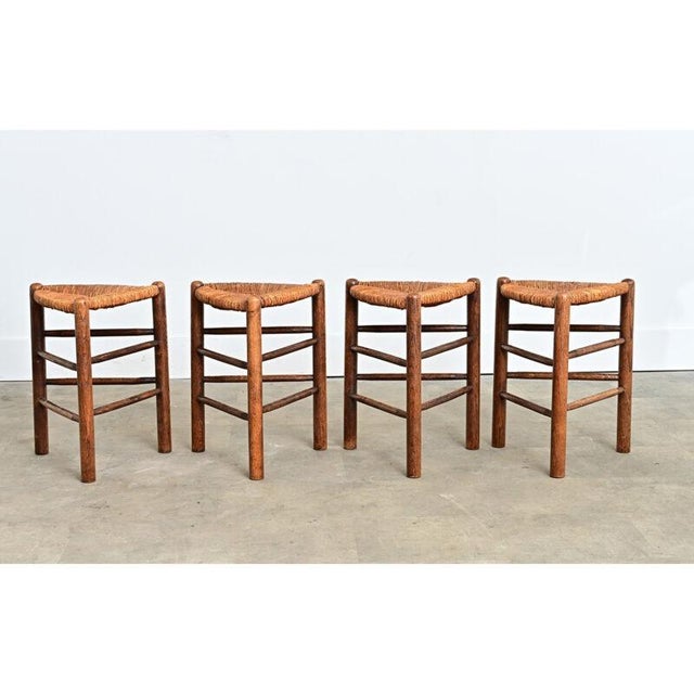 French vintage mid-century (circa 1950s) set of four triangular oak stools with rush seats in the manner of Charlotte...