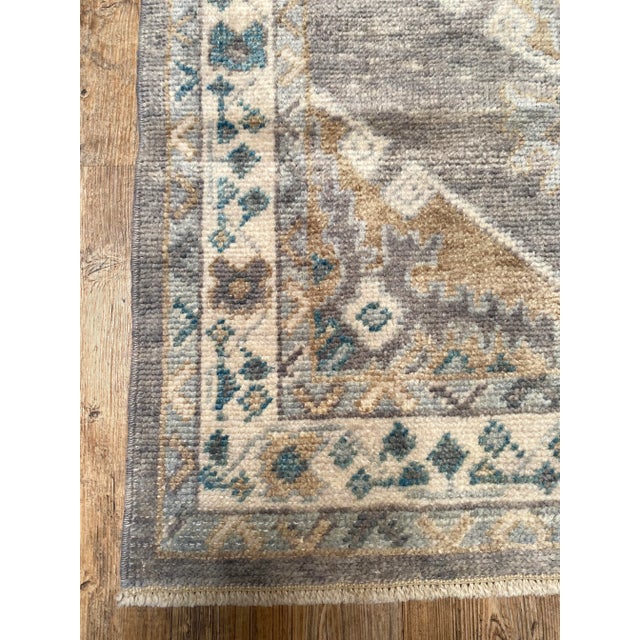 A lovely vintage Oushak runner rug. This Oushak runner offers a gray palette with blue and brown accents.