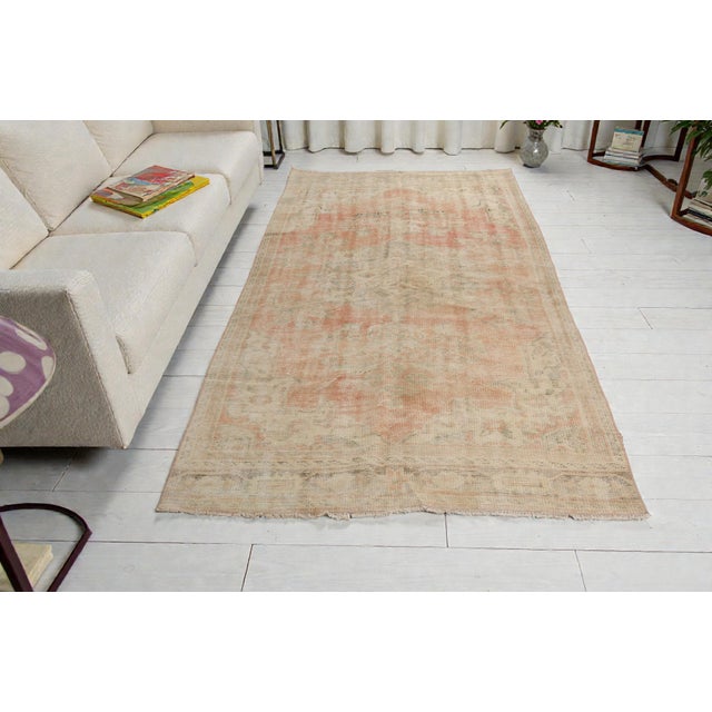 This is a vintage Turkish Oushak rug from the Mid 20th Century. The piece was hand-knotted.