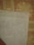 Vintage Spanish needlepoint carpet with repeating square floral motif in neutral tones.