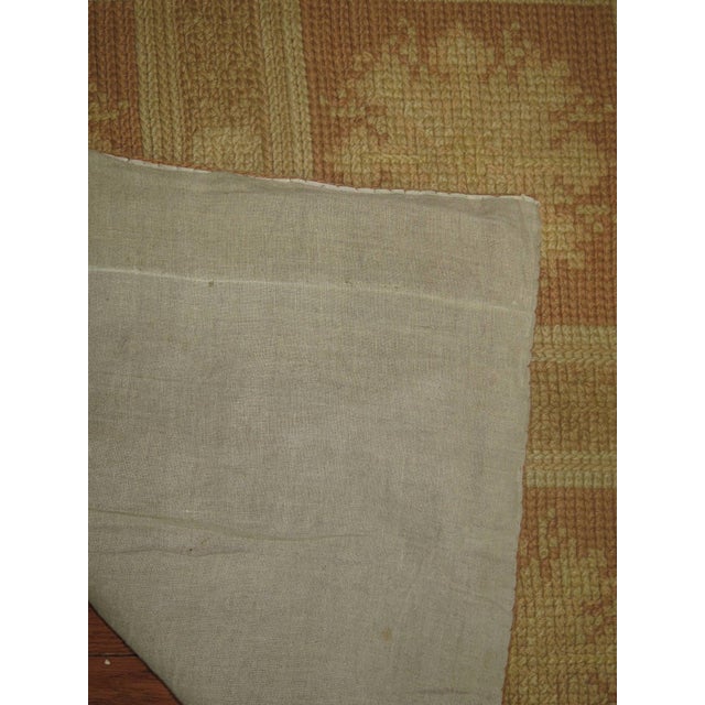 Vintage Spanish needlepoint carpet with repeating square floral motif in neutral tones.