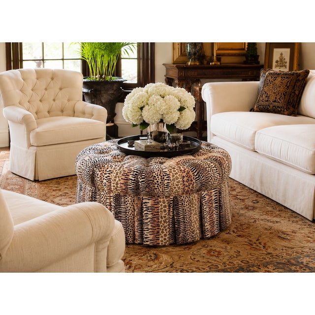 A substantial, fully upholstered cocktail ottoman featuring deep radial tufting and a tailored skirt, executed in a finely...