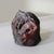 Striking handmade ceramic sculpture featuring a softly modeled human face emerging from an abstract, cocoon-like form. The...
