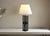 Illuminate your space in style with our Black Lacquered Rattan Table Lamp. Featuring a patinated satin black lacquer and...