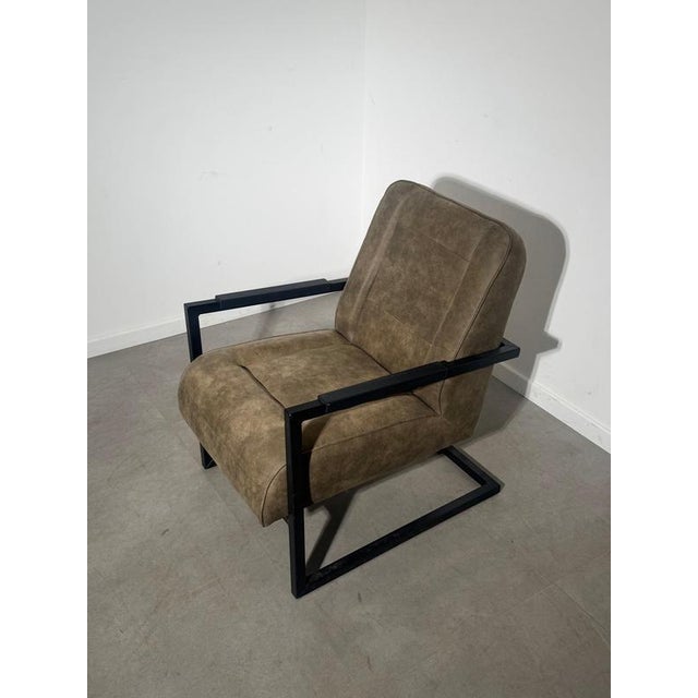 Comfortable contemporary lounge chair with a strong industrial-inspired design, featuring soft taupe/brown upholstery...