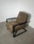 Comfortable contemporary lounge chair with a strong industrial-inspired design, featuring soft taupe/brown upholstery...