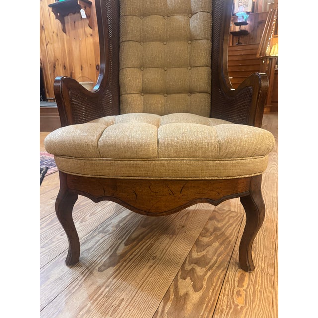 This is a vintage Lewittes cane wingback chair featuring a tufted gold velvet upholstery and intricate caning details on...