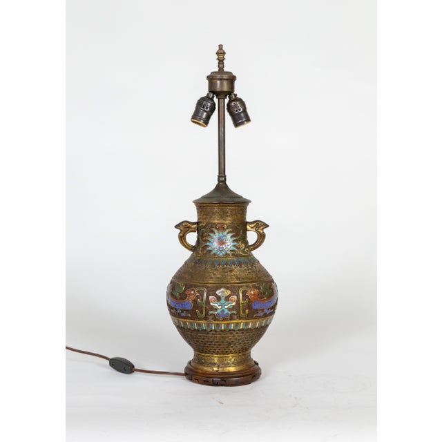 An early 20th century, patinated, cast bronze and champleve enamel vase that has been converted into a lamp; in an urn...