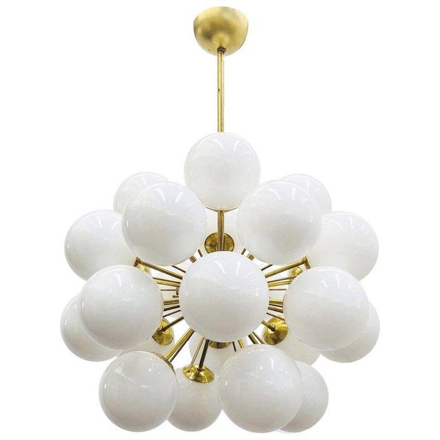 Italian sputnik chandelier with 24 glossy white Murano glass globes mounted on brass frame in unlacquered natural brass...