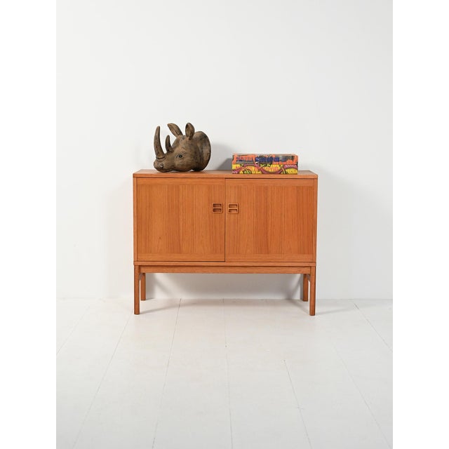 Teak cabinet with two hinged doors, carved double-drilled handles, and geometric lines that enhance the wood grain....