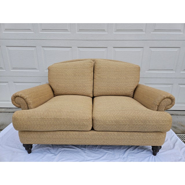 A beautiful tan and beige rolled arm loveseat with down filled cushions. This piece features a tweed fabric and sculpted...