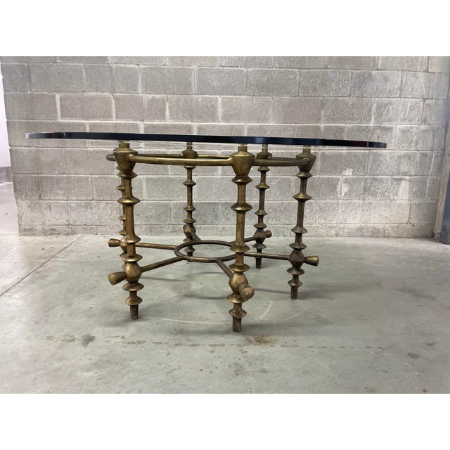 A striking mid-century brutalist dining table featuring forged metal designed base with sculptural baluster-form legs and...