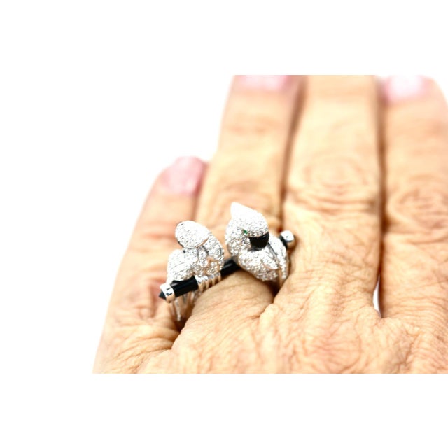 A striking cocktail ring featuring two perched cockatoos, rendered in white gold and pavé-set with round brilliant...