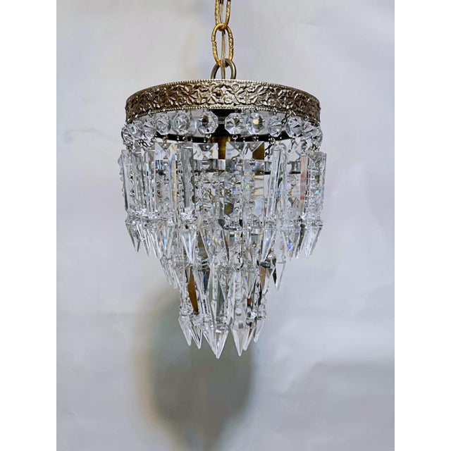 An exquisite vintage crystal waterfall chandelier featuring an elegant, tiered silhouette and beautifully detailed brass...
