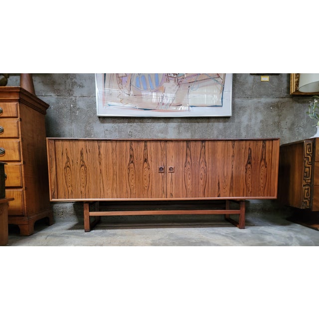 Beautiful book-matched wood grain in this 1960's rosewood Danish Modern long credenza. Tambour doors open to 3 interior...