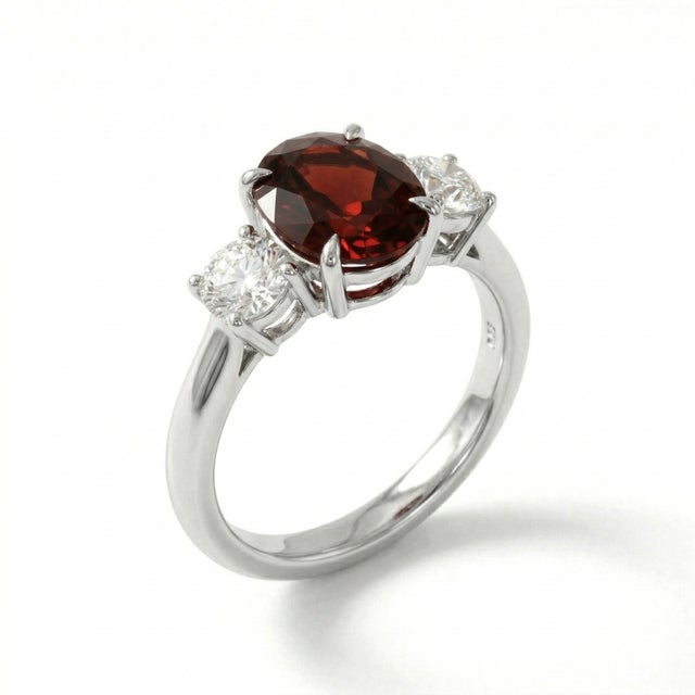 This exquisite ring showcases a striking Garnet gemstone at its center, celebrated for its deep red hue and captivating...