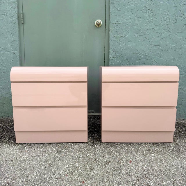 A striking pair of vintage Postmodern nightstands featuring a soft pink high-gloss laminate finish and classic waterfall...
