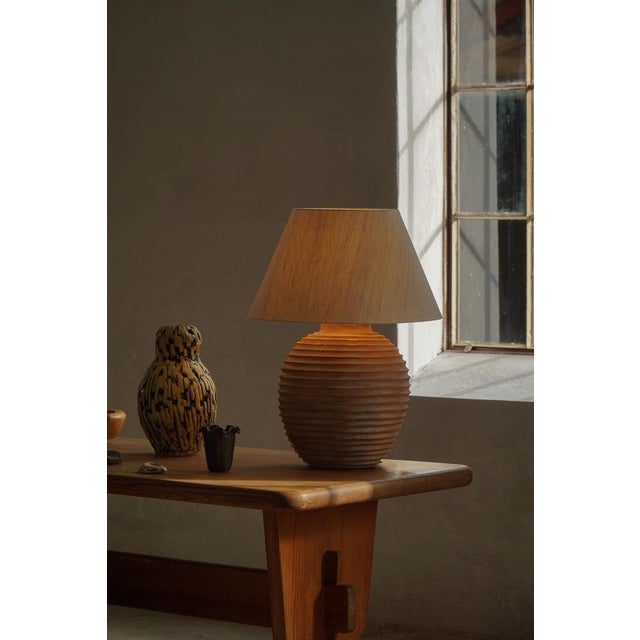A sculptural French table lamp crafted in terracotta, dating to the 1970s. The lamp is composed of a stacked series of...