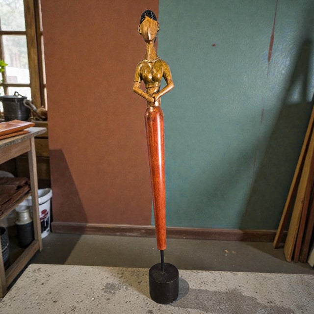 The product is a unique and stunning vintage mid-century modern hand-carved wood female sculpture standing tall at 26.75...