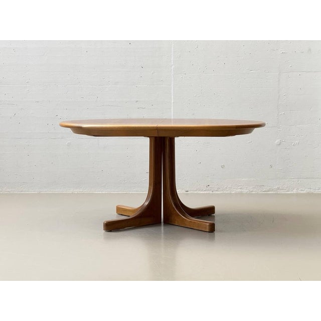 An elegant extendable dining table with a clean, scandinavian design. The oval tabletop is finished in warm teak veneer,...