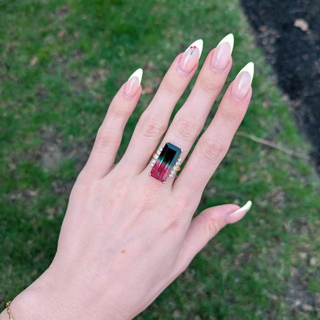 Stunning 15.1Ct bi-color tourmaline centerpiece with sparkling natural diamond accents. Set in solid 14K gold, this eye-...