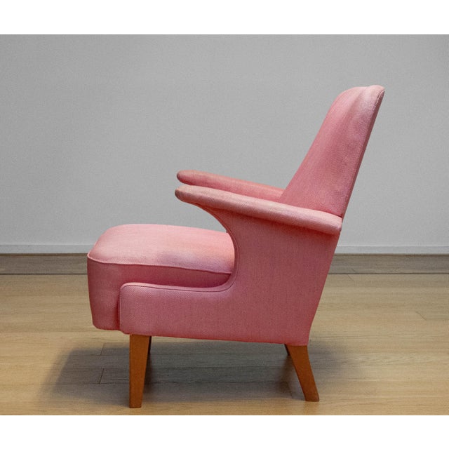The chair features a beautifully sculpted silhouette with a high gently curved backrest, distinctive sweeping armrests and...