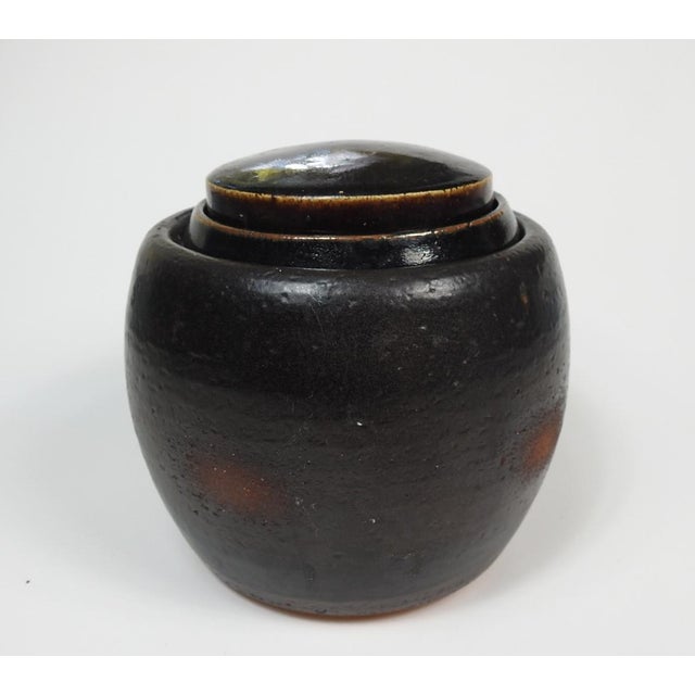 Mid 20th century brown glaze lidded pottery storage jar. The lid is in two parts and may not be the original lids as the...