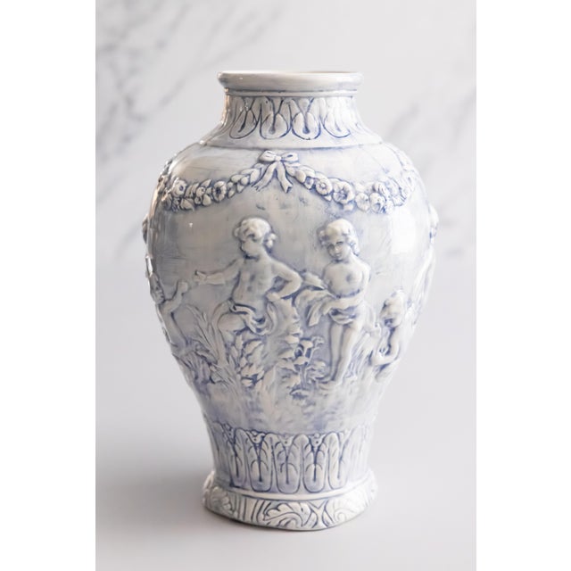 A lovely vintage Italian soft blue majolica vase decorated with frolicking cherubs or putti surrounded by draped floral...
