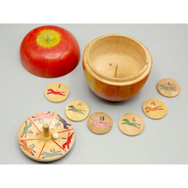 Early 20th-Century paint decorated carved apple box steeplechase horse racing game with contents. It contains a roulette...