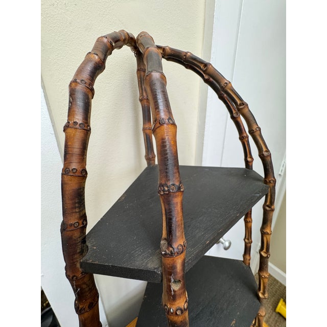 Adorable and versatile, this unusual burnt bamboo corner shelf can be hung in a corner or displayed standing. The black...