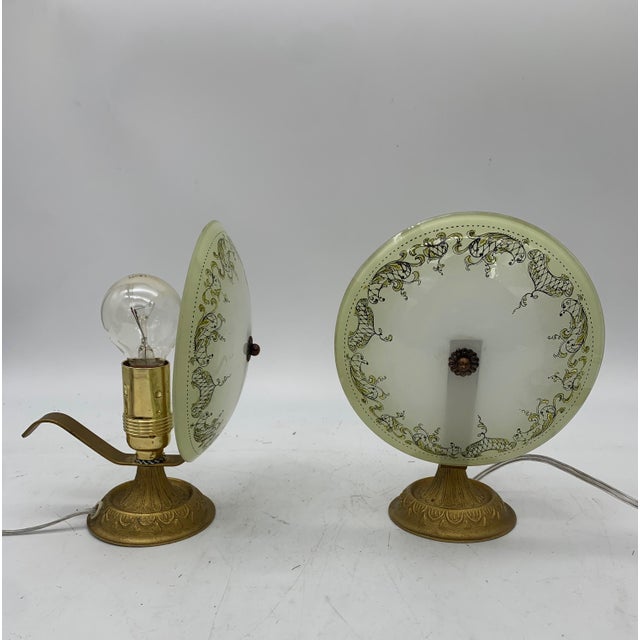 This pair of vintage table lamps features a crafted and decorated brass base, characterized by an elegant and ornamental...