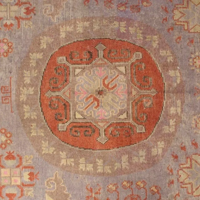 An early 20th Century Central Asian Khotan carpet with three central medallions on a light indigo background amidst a...
