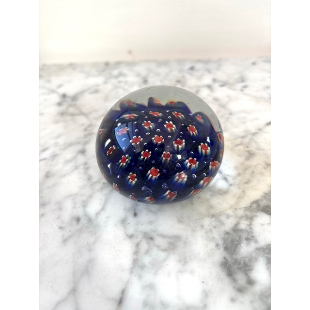 Lovely Murano glass Millefiori paperweight with red and white flowers atop a navy blue background.