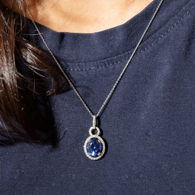 A 3.21-carat blue tanzanite oval sits at the center of this solid 14K white gold pendant, framed by forty earth-mined...