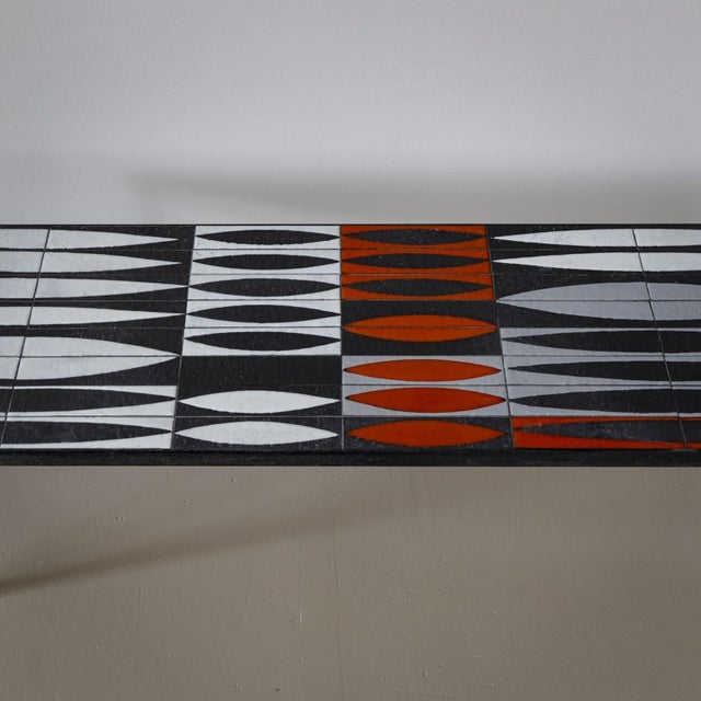 Coffee table made of a black lacquered iron frame and a rectangular tabletop of ceramic tiles. These tiles feature a...
