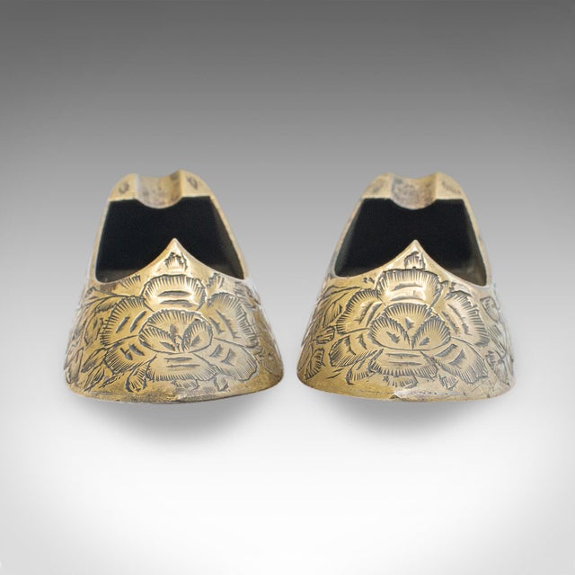 This is a pair of small vintage slipper ashtrays. An Indian, brass cigarette rest in miniature babouche shoe form, dating...