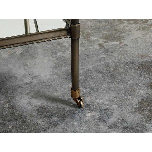 An Italian vintage trolley from the mid 20th century, with patinated metal, mirrored shelves and casters. Created in Italy...