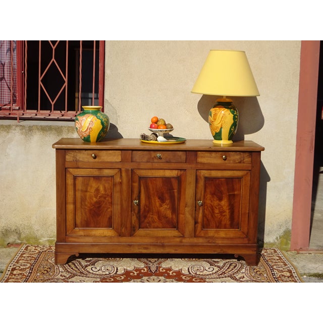 A 19th-century french-made, three-door, three-drawer sideboard. This antique piece is crafted from solid elm, assembled...