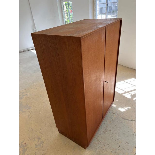 This large wardrobe, crafted from exquisite teak, is a prime example of mid-century German furniture design, bringing...