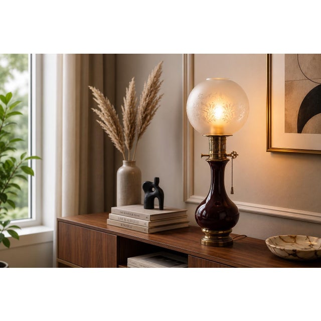 Glass and brass table lamp dating to the 1950s. The amber-brown glass base has a rounded body and slender neck, topped by...