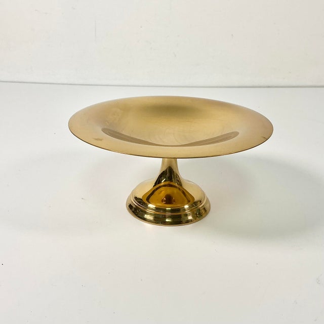 This is a small brass Bob Bon Compote from the Mid-Century. It has an overall smooth brass surface and sits on a pedestal....