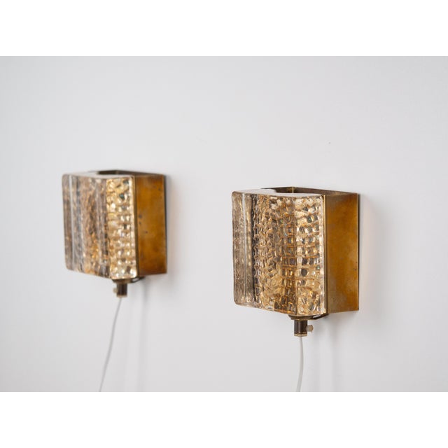 A pair of brutalist brass Maritim wall lamps. Their raw, sculptural form and geometric construction evoke the design of...