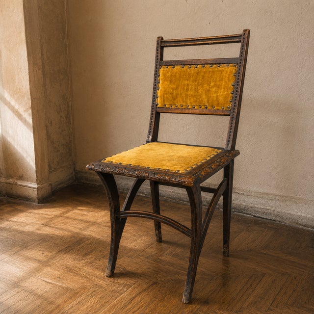 A distinctive Art Nouveau dining chair with carved solid wood detailing, mustard-yellow velvet upholstery, and brass...