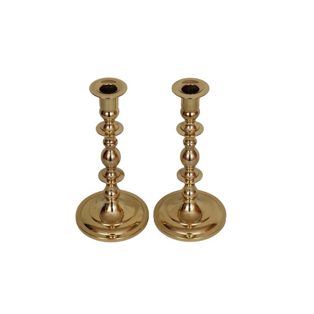 A pair of traditional turned candlesticks made of brass. Simple capitals top stems turned with double knops, finished with...