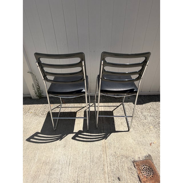 Stylish pair of vintage bar stools dating to approximately the 1970s–1980s. Each stool features a sculptural black molded-...