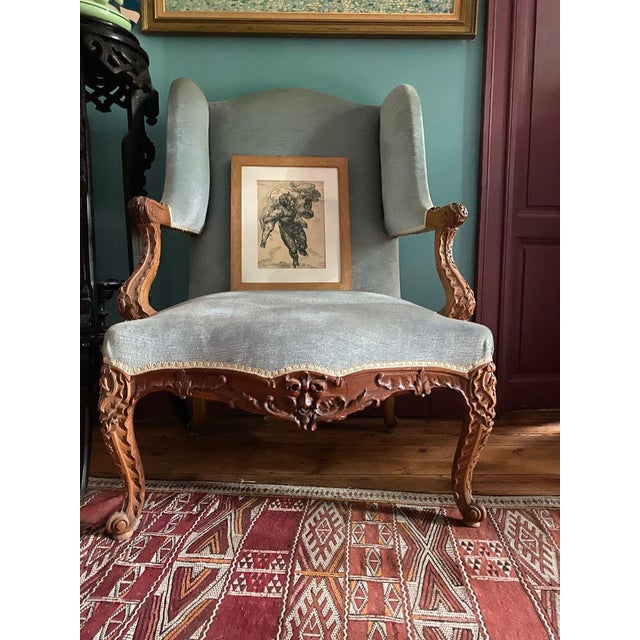 A beautiful pair of Louis XV style wingback armchairs. The frames are carved walnut decorated with flowers, foliage, and...