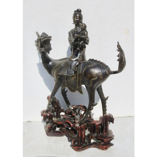 Fine bronze Kylin with a mounting of a Kuan yin with a child. Highly stylized early Qing, with a beautiful carved wooden...
