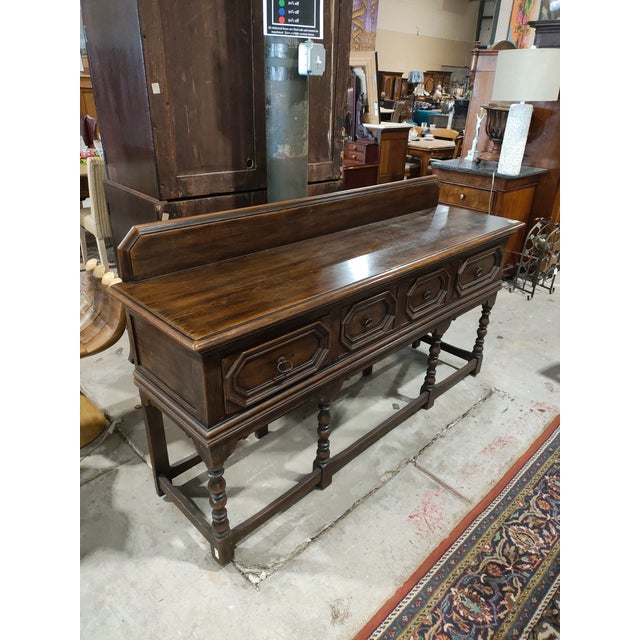 Substantial early 20th century Jacobean Revival oak server featuring four paneled drawers with original iron ring pulls, a...